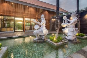 Kanhara Villas Ubud by Pramana Villas في أوبود: مسبح به تماثيل أمام المبنى