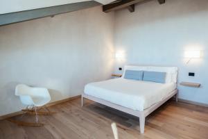 een slaapkamer met een wit bed en een witte stoel bij VINEHO in Barolo