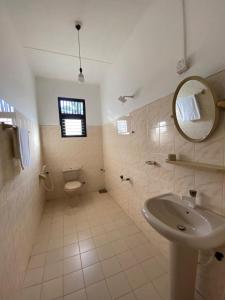 a bathroom with a sink and a toilet and a mirror at Berty's Cottage in Jaffna