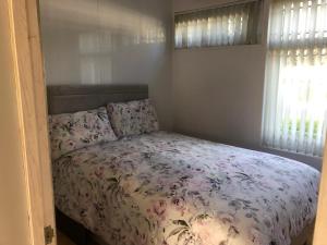 1 dormitorio con 1 cama con colcha de flores en Happy Chalet, en Pembrokeshire