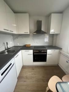 a kitchen with white cabinets and a black stove top oven at Familienwohnung neben dem See,Messe und Europapark in Offenburg