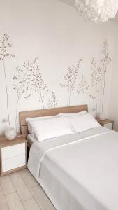 a bedroom with a bed with white sheets and flowers on the wall at B&B Le Albarelle in Alba
