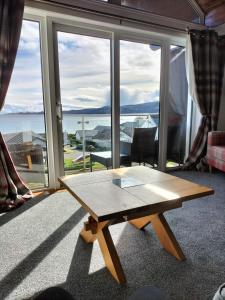 a wooden table in a room with a large window at Seaview cosy 2 bed home in Lamlash in Lamlash