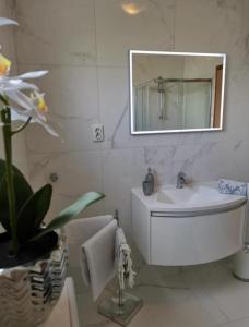 a white bathroom with a sink and a mirror at Apartment Dario in Zadar
