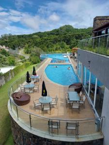 uma vista para uma piscina com mesas e cadeiras em Golden Gramado Resort em Gramado