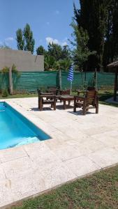 two wooden benches next to a swimming pool at ENTRE VIÑAS in Ciudad Lujan de Cuyo