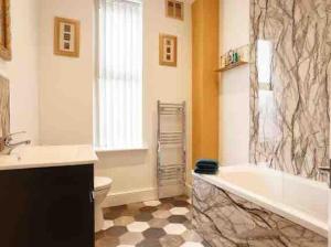a bathroom with a tub and a toilet and a sink at Luxury 2 Bedroom Home in Leeds