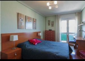 una camera con letto blu, scrivania e finestra di Alojamientos Marte apartamentos a Torrelavega