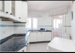 una cucina con armadi bianchi e piano di lavoro nero di Alojamientos Marte apartamentos a Torrelavega