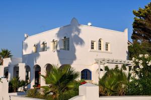 a white house with palm trees in front of it at Beachlife: The Apartment in Marmari