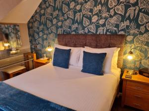 um quarto com uma cama grande e almofadas azuis em Brookside Guest House & Mini Spa em Brixham