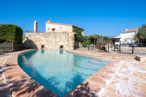 a swimming pool in front of a stone house at Lo paller in Perelló