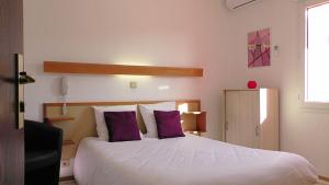 sypialnia z dużym białym łóżkiem z fioletowymi poduszkami w obiekcie Aubergade w mieście Barbotan-les-Thermes