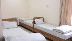 a room with three beds with white sheets at Apple Hostel Bishkek in Bishkek