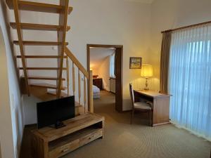 Zimmer mit einer Treppe und einem Schreibtisch mit einem TV in der Unterkunft Appartment-Hotel-Hölzl in Grünwald