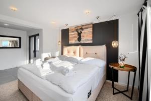 Cette chambre comprend un grand lit blanc et une table. dans l'établissement AP Baltic Mielno, à Mielno