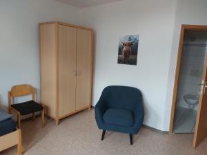 a room with a blue chair and a cabinet at Gästehaus Heinrich Heine Schule in Bad Dürrenberg