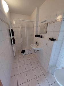 a white bathroom with a sink and a shower at Gästehaus Heinrich Heine Schule in Bad Dürrenberg