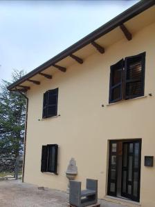 - un bâtiment blanc avec des fenêtres noires et une chaise dans l'établissement La lepre nella Luna, à Gualdo Tadino
