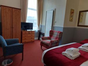 una camera d'albergo con letto, sedia e TV di The Norwood a Torquay