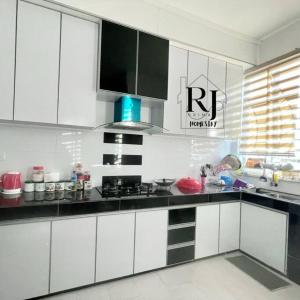 una cocina con armarios blancos y encimeras negras en RJ Prima (UMT, UniSZA, Spacious, Beach + Netflix), en Kuala Terengganu