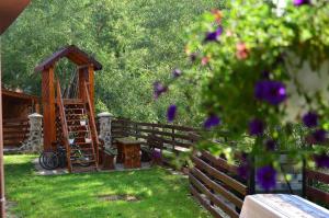 a garden with a wooden fence and a gazebo at Pensiunea Valea Galbenei in Arieşeni