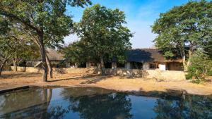 una casa con un estanque delante de ella en Gwango Elephant Lodge en Dete