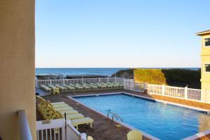 a pool with chairs and the ocean in the background at Surf Side Hotel in Nags Head