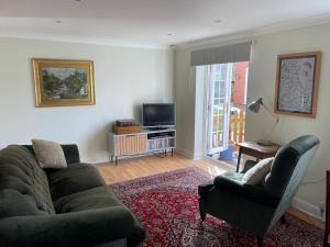 Una sala de estar con un sofá, una silla y un televisor. en The Garden House, en Bishop Burton
