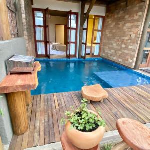 a swimming pool on a wooden deck with a table and a table at Kaha Mar - Patacho in Pôrto de Pedras