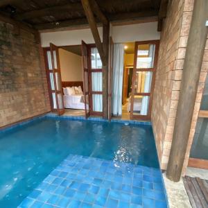 a swimming pool in a house with a brick wall at Kaha Mar - Patacho in Pôrto de Pedras