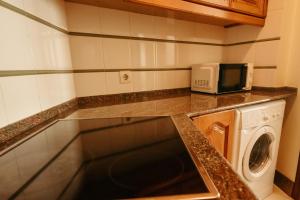 a kitchen with a microwave and a washing machine at LAR DA REVOLTA in Cedeira