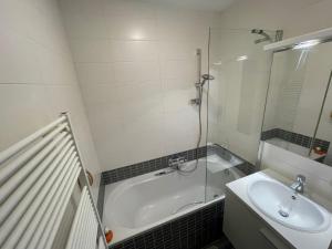 a bathroom with a bath tub and a sink at Marktplein Middelkerke in Middelkerke +6 photos