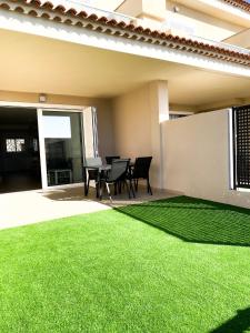 a patio with a green lawn in front of a house at Playa Negra Holiday in Puerto de Santiago