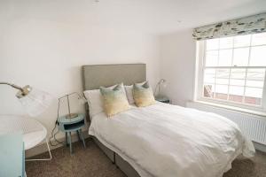 a white bedroom with a bed and a window at Woodyear House - Cowes - Sleeps 8 - 4 Bed - Dog Friendly - Waterfront in Cowes