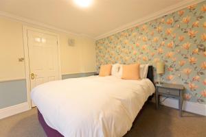 a bedroom with a large white bed with floral wallpaper at Woodlands Lodge Hotel in Bartley