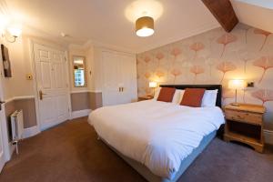 ein Schlafzimmer mit einem großen weißen Bett mit orangefarbenen Kissen in der Unterkunft Woodlands Lodge Hotel in Bartley