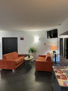 una sala de estar con 2 sofás naranjas y una mesa. en Logis Cottage Hôtel, en Calais