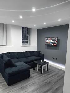 a living room with a black couch and a tv at Contemporary Comfort - Central Bradford Flat in Bradford