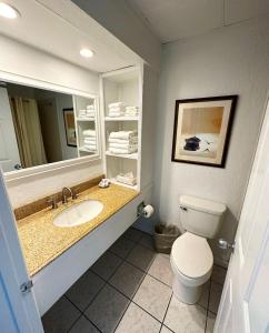 a bathroom with a sink and a toilet and a mirror at Surf Side Hotel in Nags Head