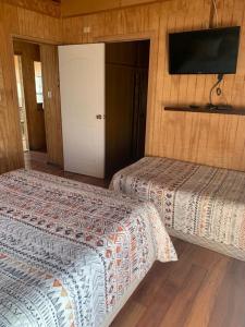 a bedroom with two beds and a flat screen tv at Cabañas Bosque Sur in Puerto Varas