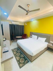 een slaapkamer met een wit bed en een gele muur bij Royal Beach International in Puri