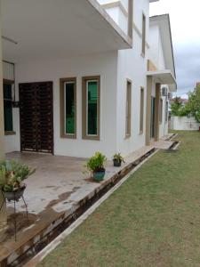 a white house with potted plants in a yard at Family Homestay Taman Vistana Indah Alor Setar in Langgar