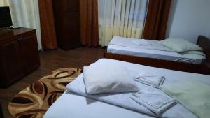 - une chambre avec 2 lits avec des draps blancs dans l'établissement Pensiunea Valea Galbenei, à Arieşeni