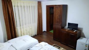 Cette chambre comprend un lit, une télévision et une commode. dans l'établissement Pensiunea Valea Galbenei, à Arieşeni
