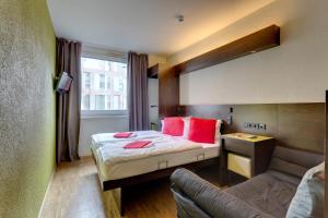 a bedroom with a couch, chair, table and a window at MEININGER Hotel Berlin Hauptbahnhof in Berlin