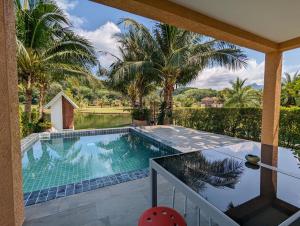 a swimming pool in a yard with palm trees at Blue Cove Pool Villa in Trat