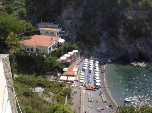 a beach with umbrellas and boats in the water at Villa la caletta in Maiori