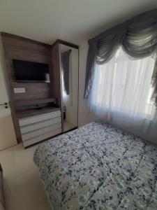 Schlafzimmer mit einem Bett, einem TV und einem Fenster in der Unterkunft Apartamento inteiro com garagem coberta Treviso in União da Vitória