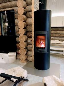 una chimenea con chimenea en la sala de estar en Upea kelohirsihuvila rannalla, myös poreamme! en Joensuu